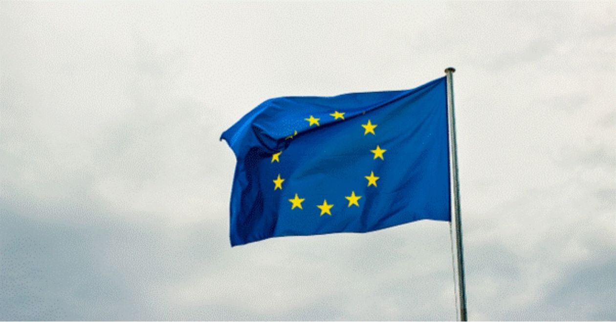 A bandeira tem um fundo azul, semelhante ao da União Europeia, com um círculo de estrelas douradas no centro. As estrelas representam os países membros do tratado, simbolizando unidade e colaboração. O azul transmite a ideia de paz e estabilidade.